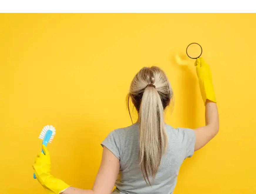 żółte tło, pani blondynka sprawdza czystość na ścianie